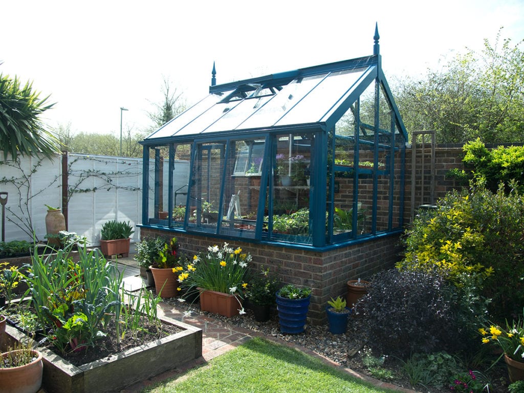 Blue three quarter span greenhouse in Hampshire garden