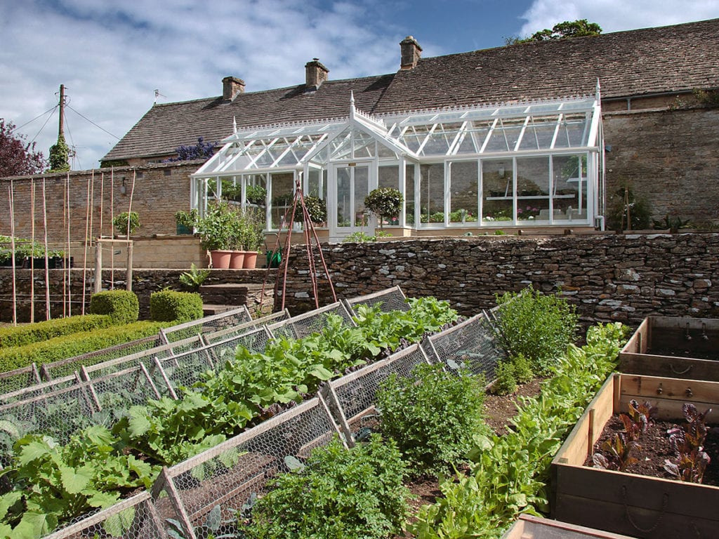 Three quarter span greenhouse in kitchen garden in Gloucestershire
